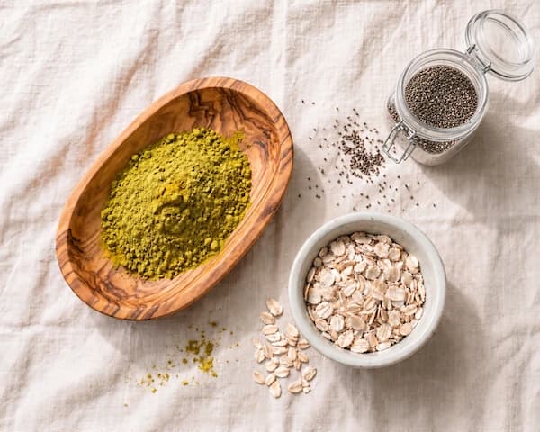 A flat lay of PersoMIX ingredients — pea protein, sweet potato, banana, chia and oats on linen